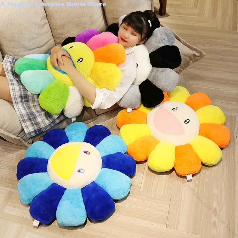 A large, colorful sunflower plush cushion with yellow and orange petals is shown on a wooden floor.