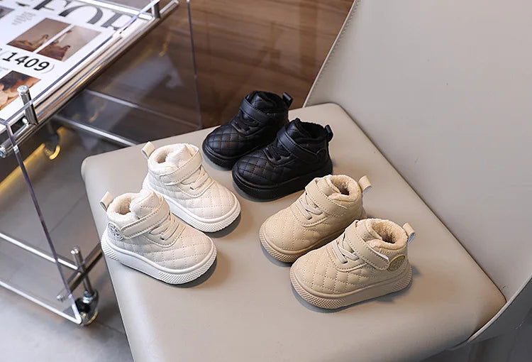 A collection of toddler winter snow boots in black and beige leather, displayed on a light surface.