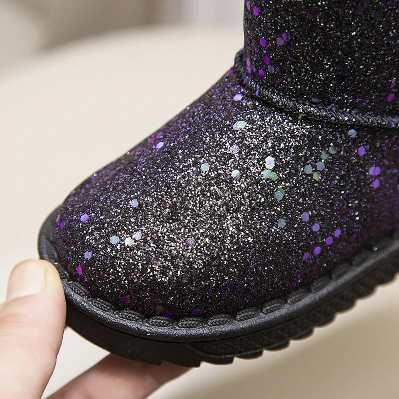 A close-up of a purple glitter snow boot being held, showing the textured fabric and black sole.