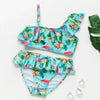 A turquoise and floral two-piece swimsuit set for girls featuring tropical leaves and colorful flowers.