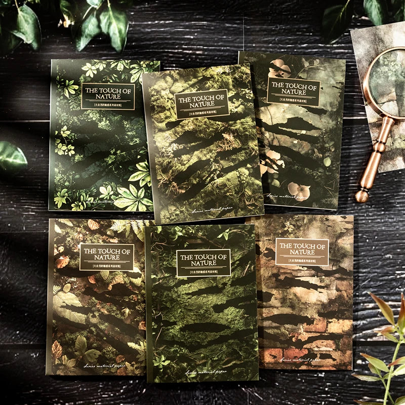 A collection of vintage nature scrapbook paper sheets in various shades of green and brown, displayed on a dark wooden surfac