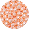 A close-up view of small, round, pink imitation pearl beads for DIY jewelry making.