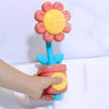 A hand is holding a pink and yellow sunflower bath shower sprinkler toy for kids.
