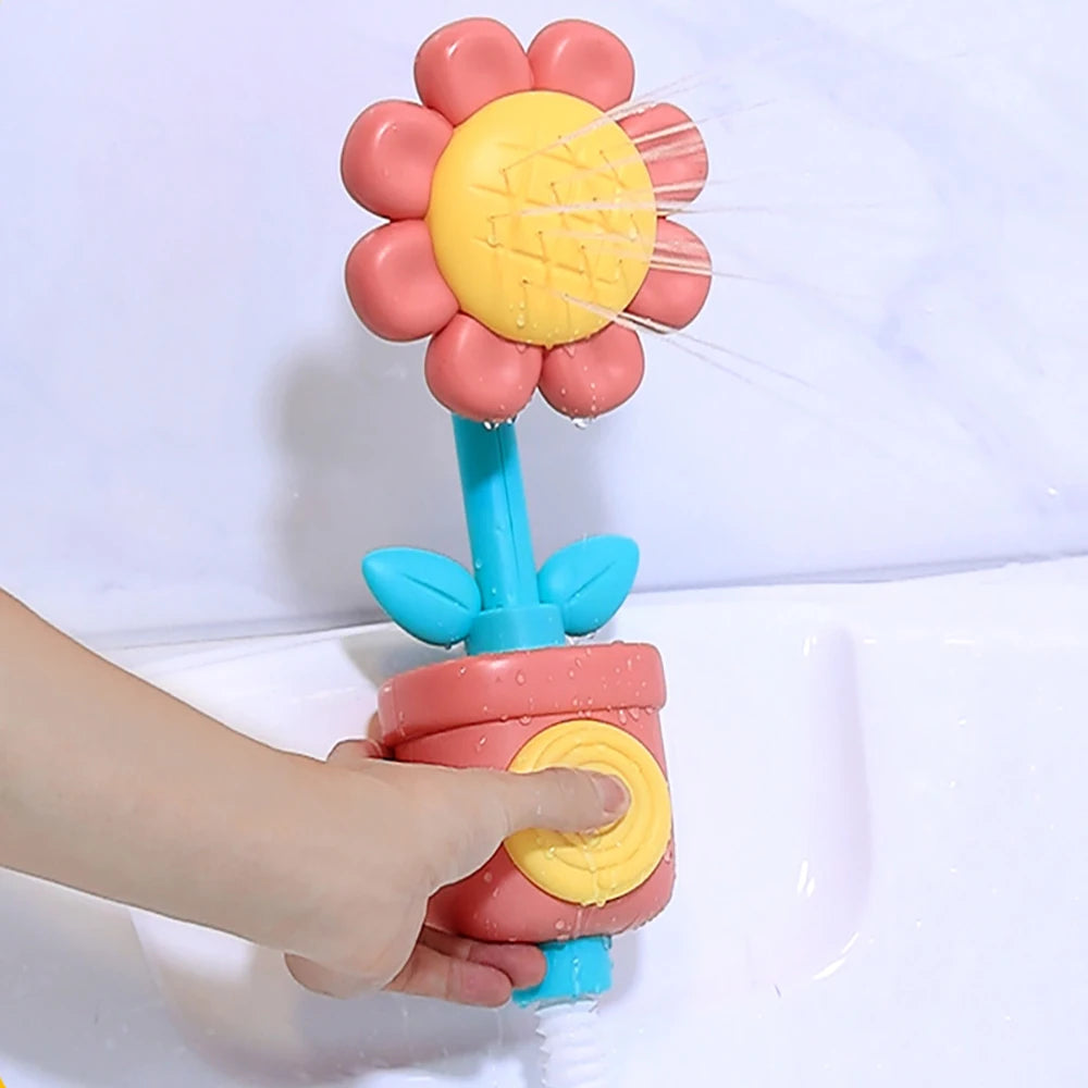 A hand is holding a pink and yellow sunflower bath shower sprinkler toy for kids.