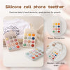 A silicone cell phone teether toy with colorful buttons and a mobile attachment shown next to a baby's hand.