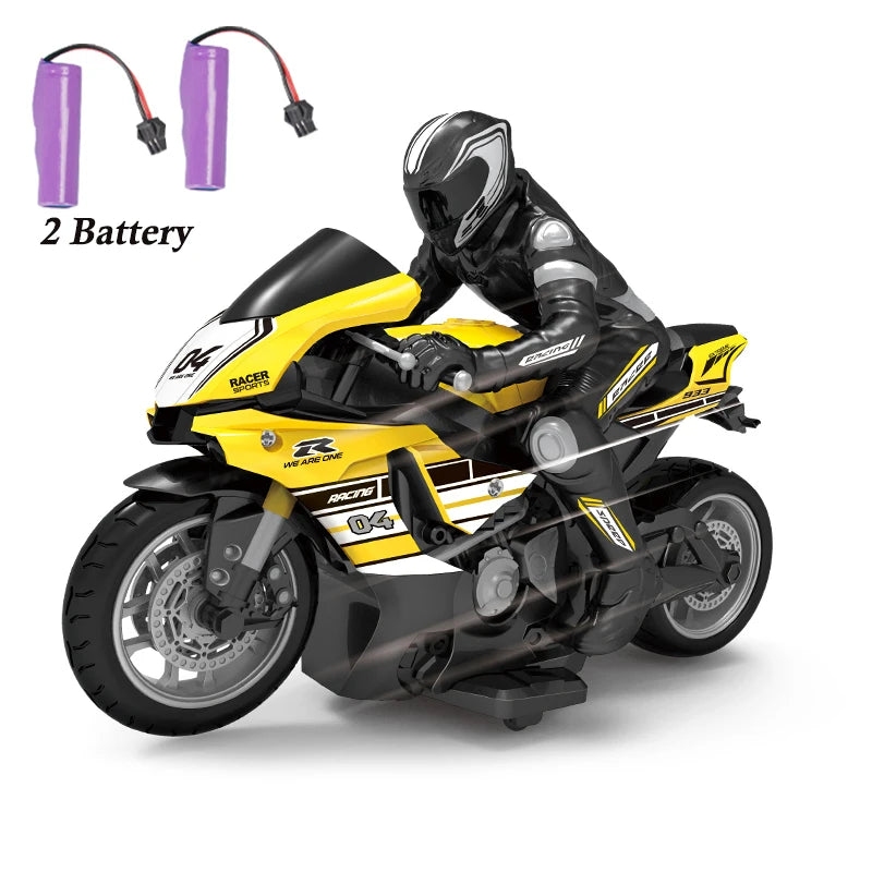 A black and yellow 1:10 scale remote control stunt motorcycle with a rider figure and two batteries.