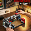 A hand is assembling a building block set depicting a vintage American garage scene with various miniature vehicles and tools