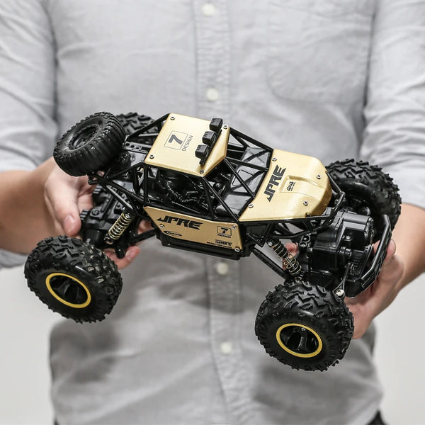 En person håller en svart och guld 1:16 skala 4WD terrängradiostyrd bil.