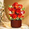A vibrant bouquet of red roses and white filler flowers displayed in a pot with warm string lights.