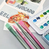 A set of six nylon paint brushes in various shades of pink and green laid out on a gray surface.