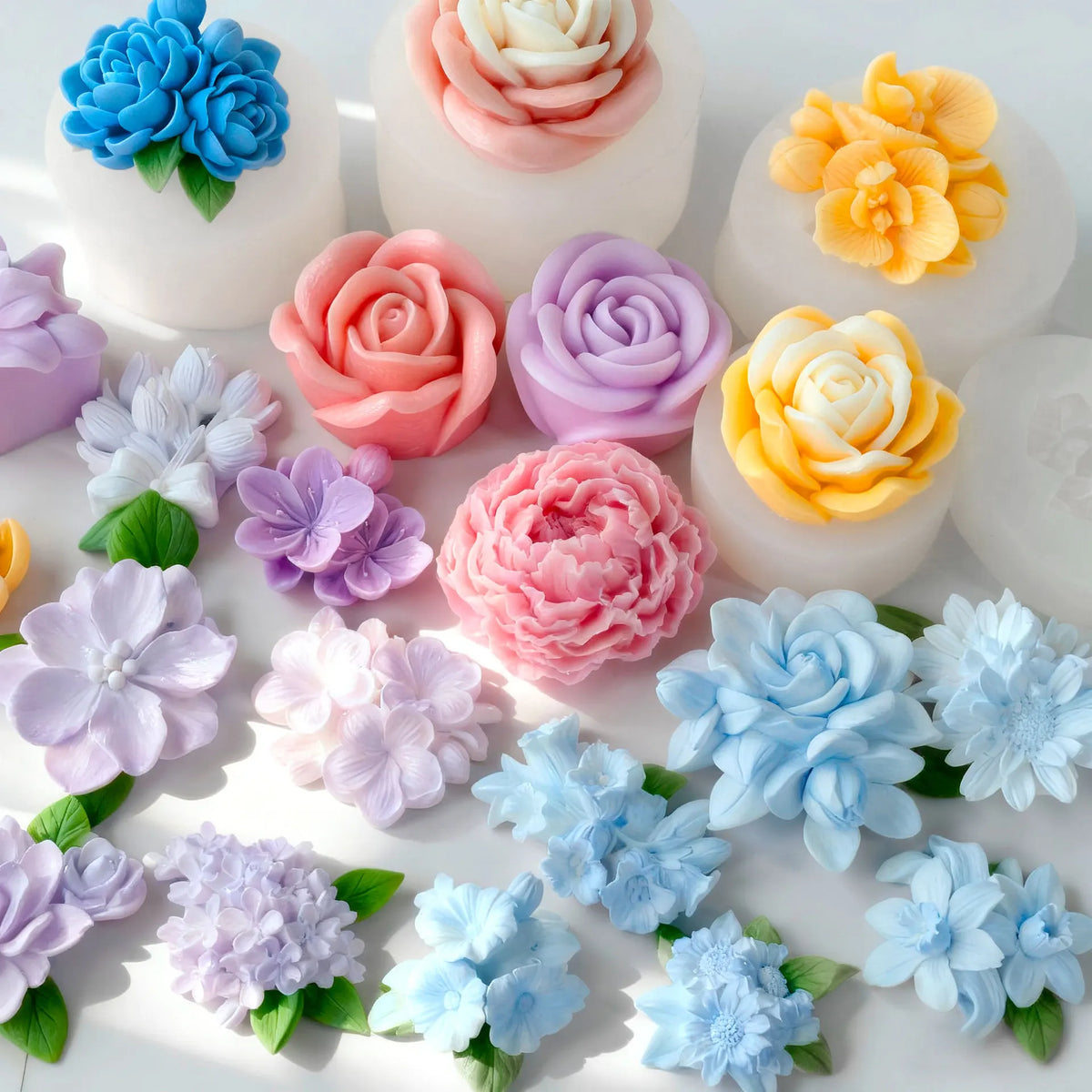 A collection of multi-flower silicone molds in various shades of pink, blue, and yellow used for DIY crafting.