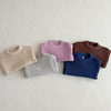 A row of five knitted baby pullovers in pastel and earthy tones laid flat on a light background.
