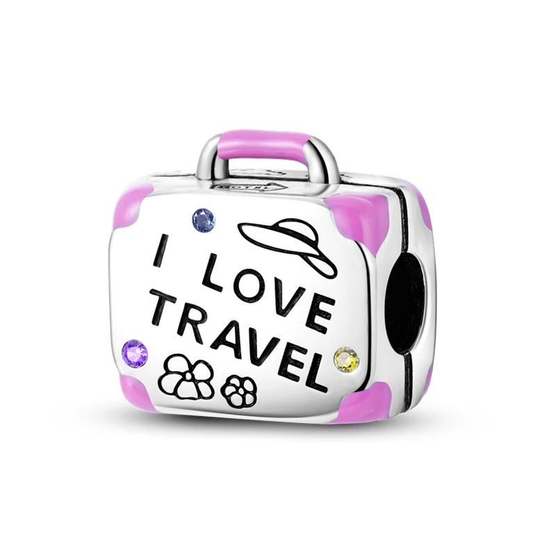 A silver heart-shaped charm bead with a pink zircon and the text I love travel engraved on it.
