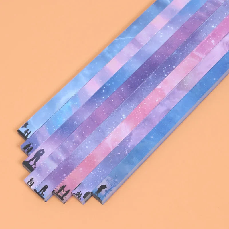 A collection of 27 narrow, iridescent paper strips in various pastel colors and glitter patterns for crafting.