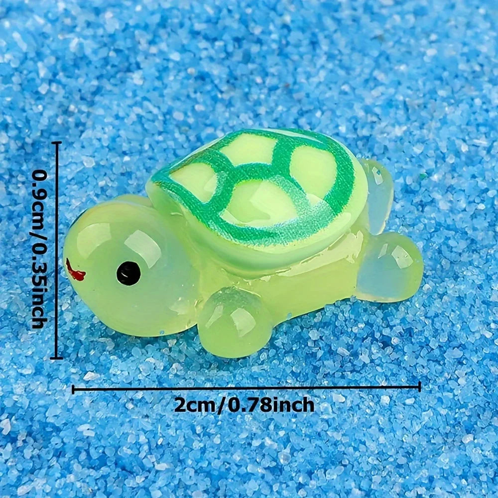 A small, translucent lime green glow-in-the-dark turtle collectible figurine resting on a blue, sparkly surface.