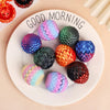 A white plate features six colorful, textured 3D dragon egg surprise figurines in various shades of purple, green, orange, an