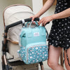 A woman holds a light blue backpack with a patterned design and wet/dry separation features.