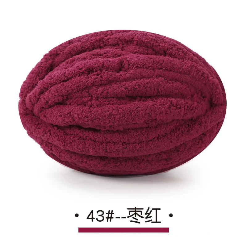 A ball of deep magenta chunky chenille yarn for hand knitting projects.