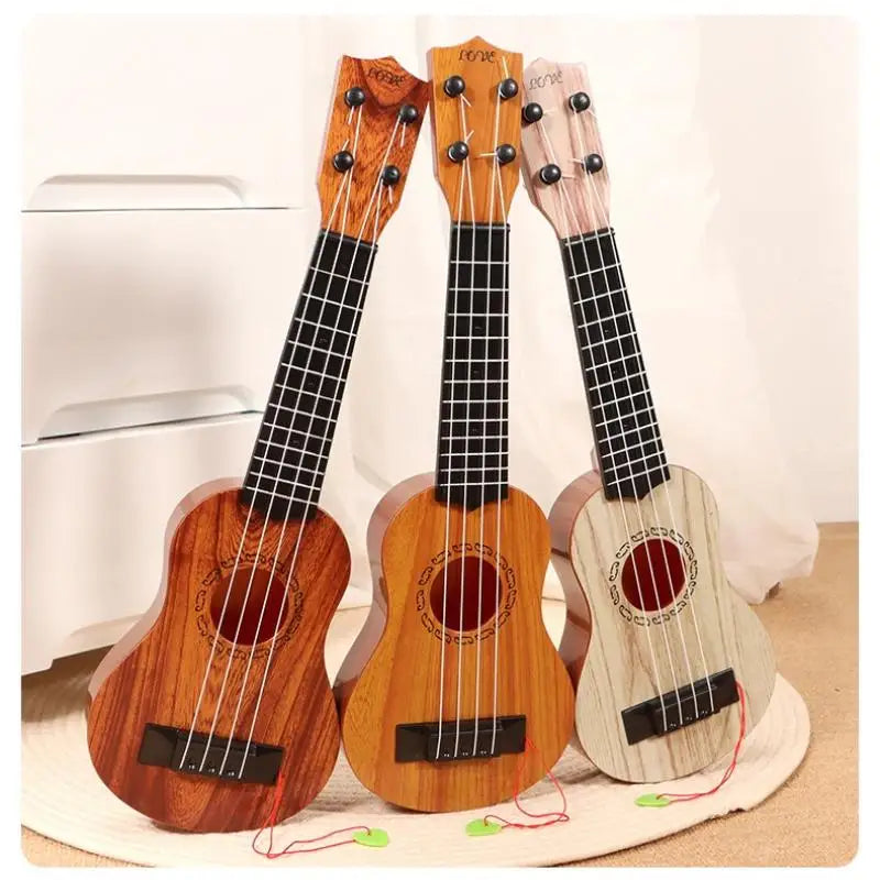 Three wooden toy guitars, including a ukulele-style instrument, are displayed on a light surface.