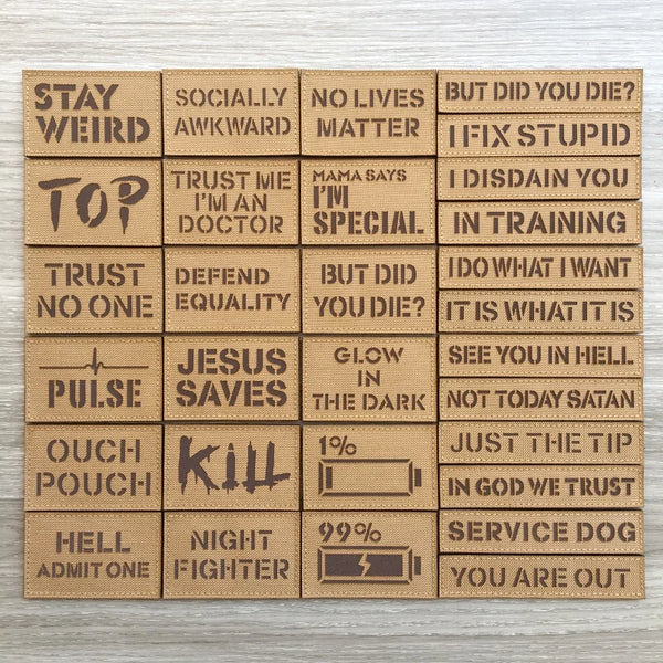 A collection of brown tactical morale patches featuring various phrases like STAY WEIRD, KILL, and I FIX STUPID.