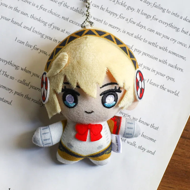 A fluffy blonde anime character plushie pendant charm with large blue eyes and a red bow.