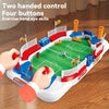 A hand operating a mini tabletop foosball game with four buttons and two hands to control the players on the green field.