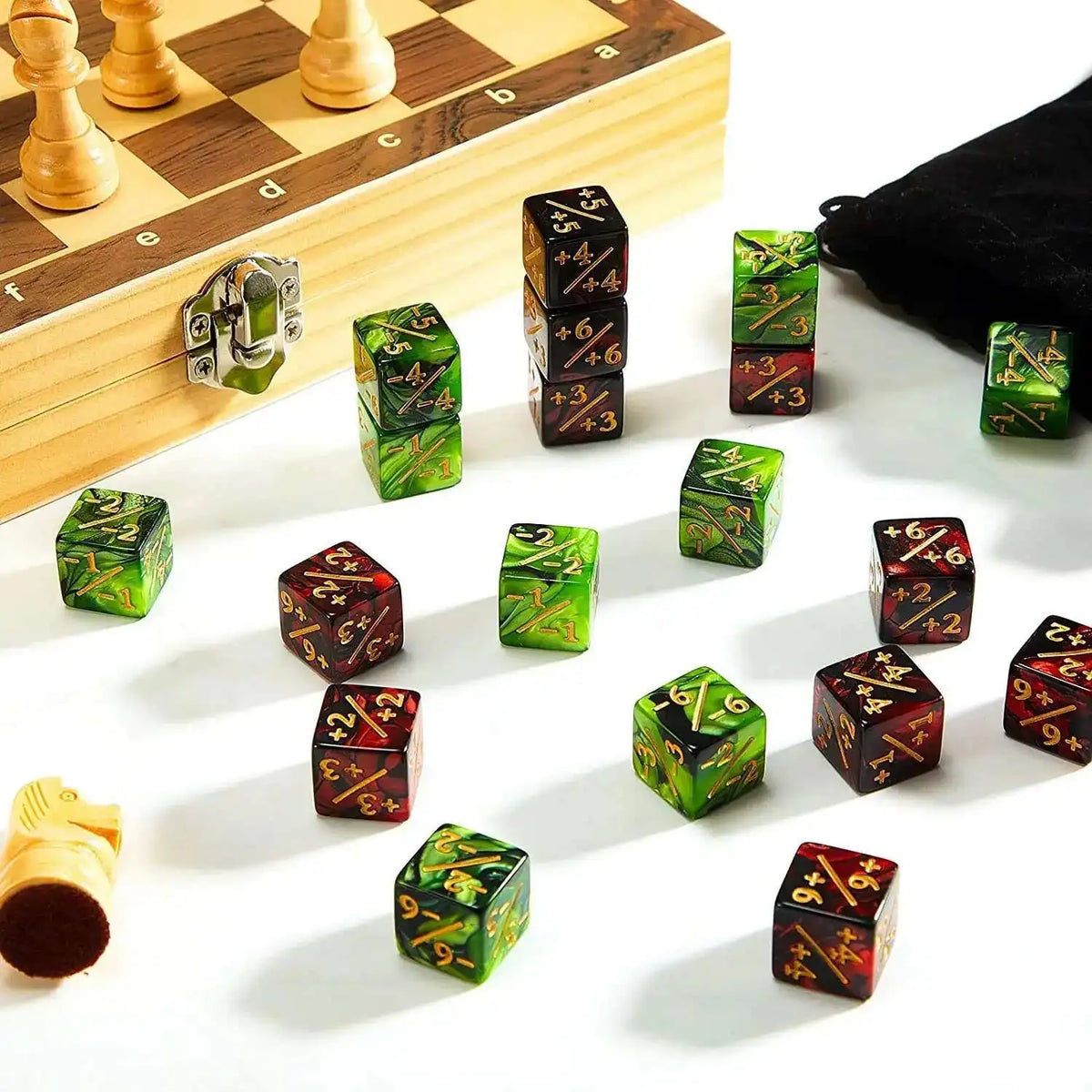 A collection of ten dual-color +1/-1 counting dice arranged on a white surface next to a wooden chessboard.