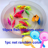 A clear dish contains ten colorful fish toys and one fishing net toy.