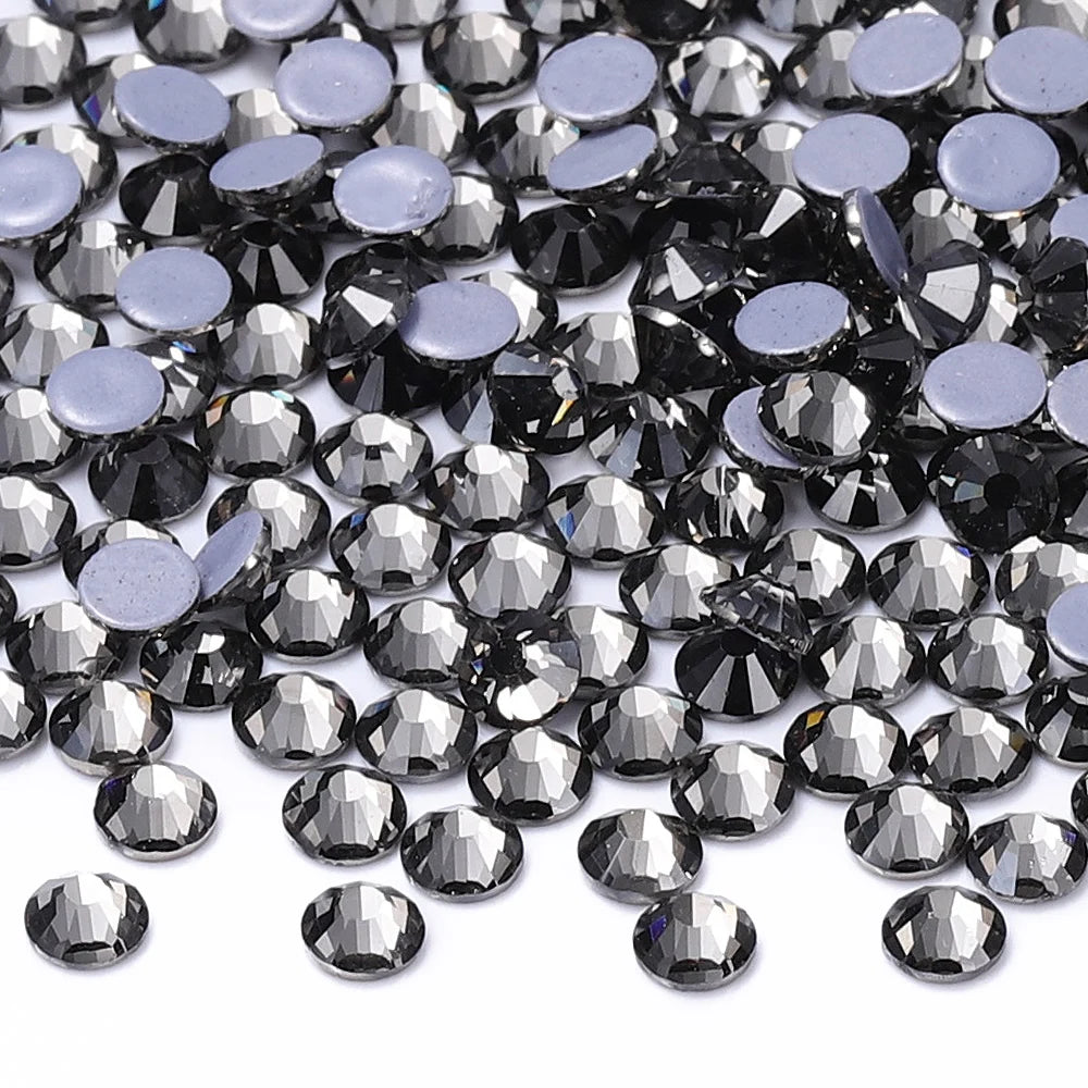 A close-up view of various clear and purple glass crystal rhinestones scattered on a white background.