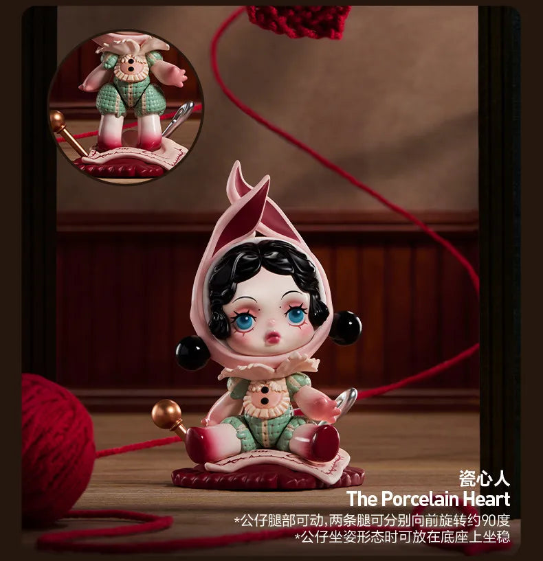 A porcelain heart collectible figure with dark hair and blue eyes sitting on a pink base.