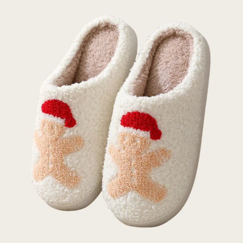 A pair of white plush non-slip indoor slippers with small red Santa-themed appliqués.