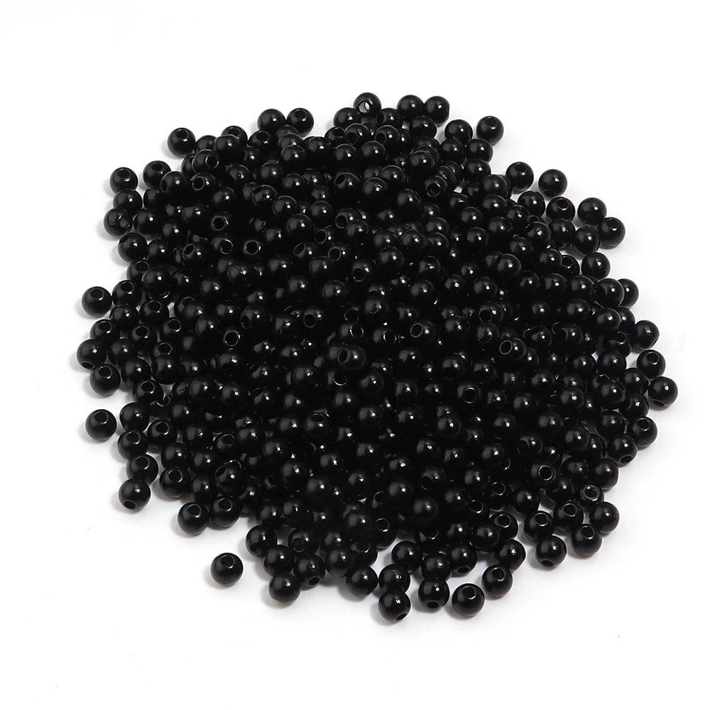 A pile of small, round, black imitation pearl beads for jewelry making.
