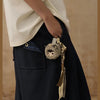 A dark navy fabric garment with a pocket features a small keychain charm of a gray animal.