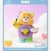 A yellow Care Bear figurine with a purple vest and green pants is shown against a soft white background.