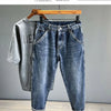 A pair of dark blue vintage loose fit denim harem jeans displayed on a wooden hanger.