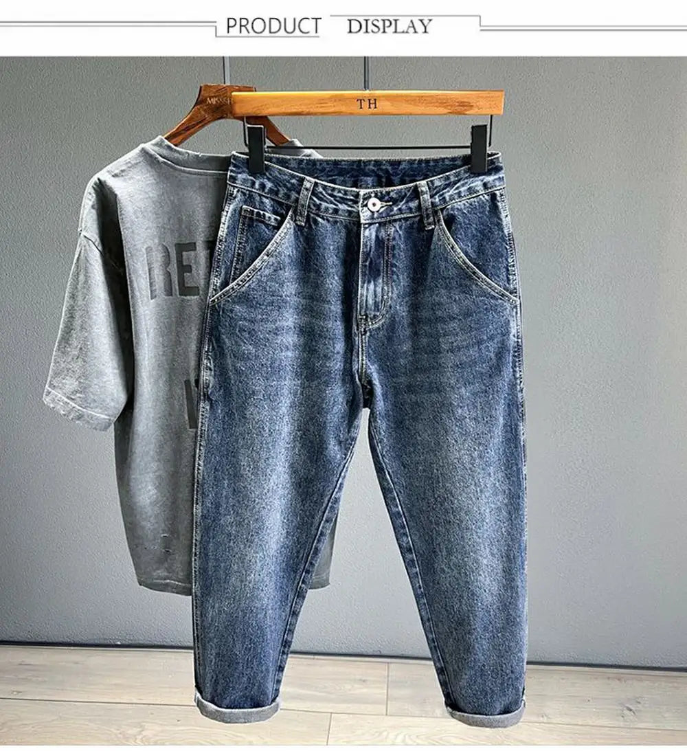 A pair of dark blue vintage loose fit denim harem jeans displayed on a wooden hanger.