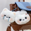 A fluffy white rabbit plush charm attached to a brown leather handbag.