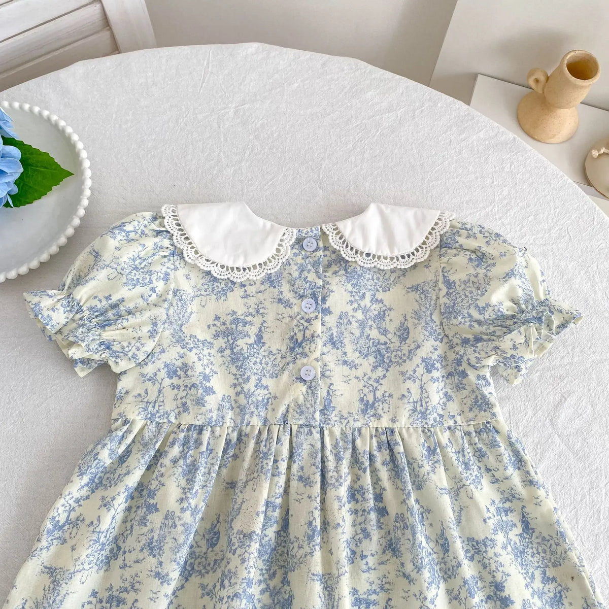 A light yellow floral dress for girls with white scalloped collar and puff sleeves.