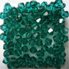 A pile of faceted teal green glass bicone beads for jewelry making.