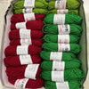 A box filled with various skeins of green and red yarn for knitting and crochet crafts.