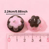 Two pink and black pudding-shaped resin pendants are shown next to a ruler for scale.
