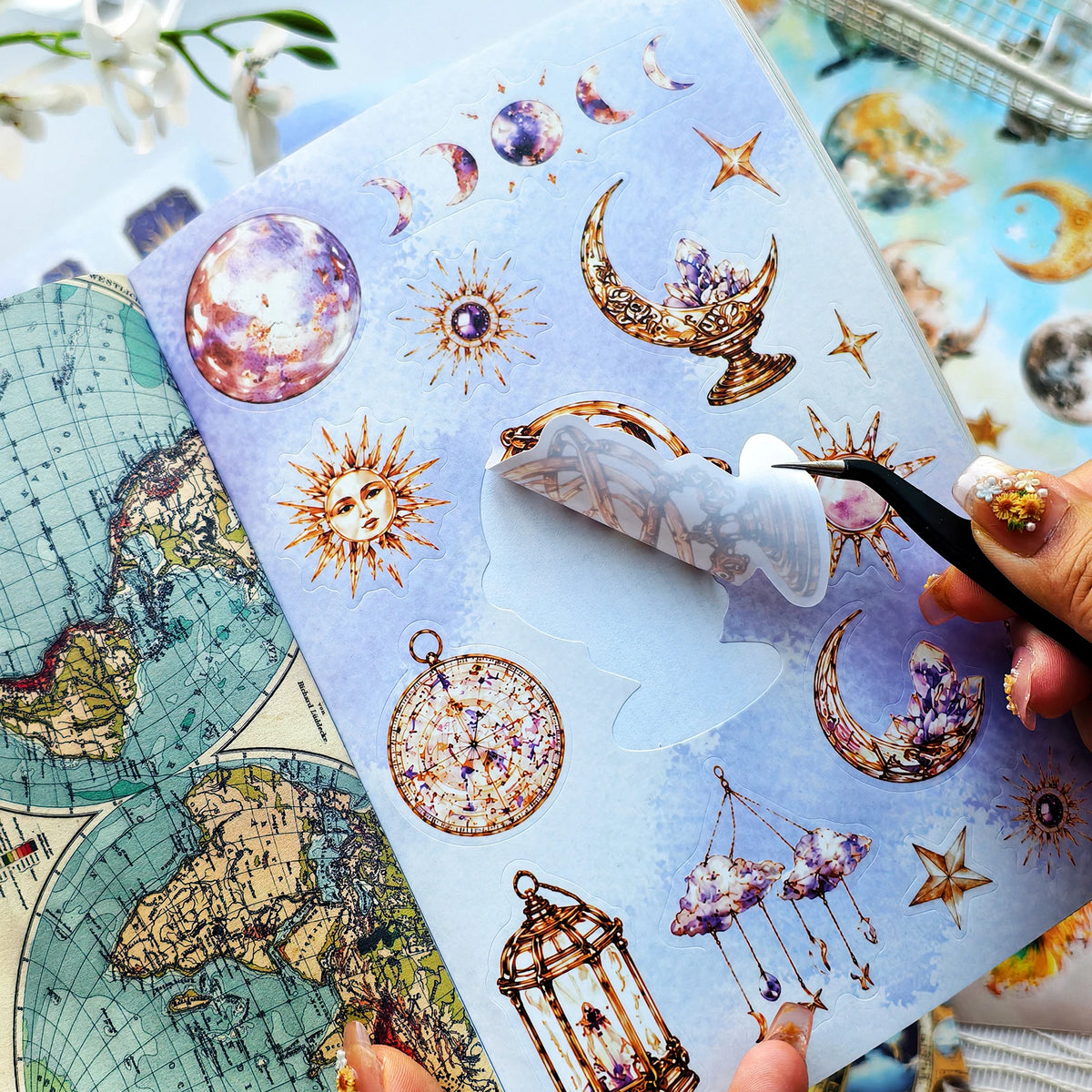 A hand holds an open journal featuring retro astronomy stickers, including planets, stars, and moons.