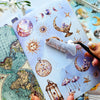 A hand holds an open journal featuring retro astronomy stickers, including planets, stars, and moons.