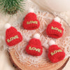 A set of mini knitted red hats with white pom-poms and gold LOVE embroidery displayed on a lace fabric background.