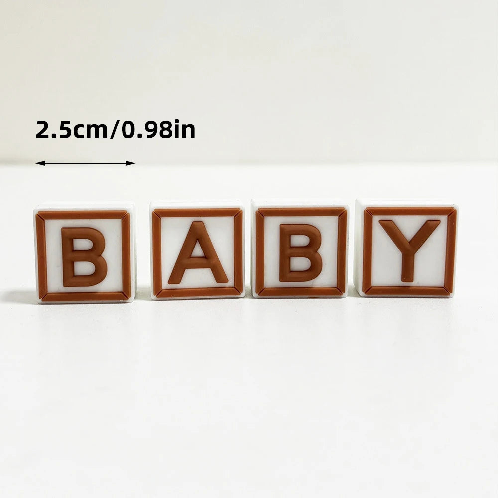 Three wooden letter cake toppers spelling BABY in brown and white colors