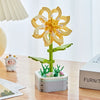 A yellow rose flower building block bouquet set with green stems and leaves displayed on a wooden table.