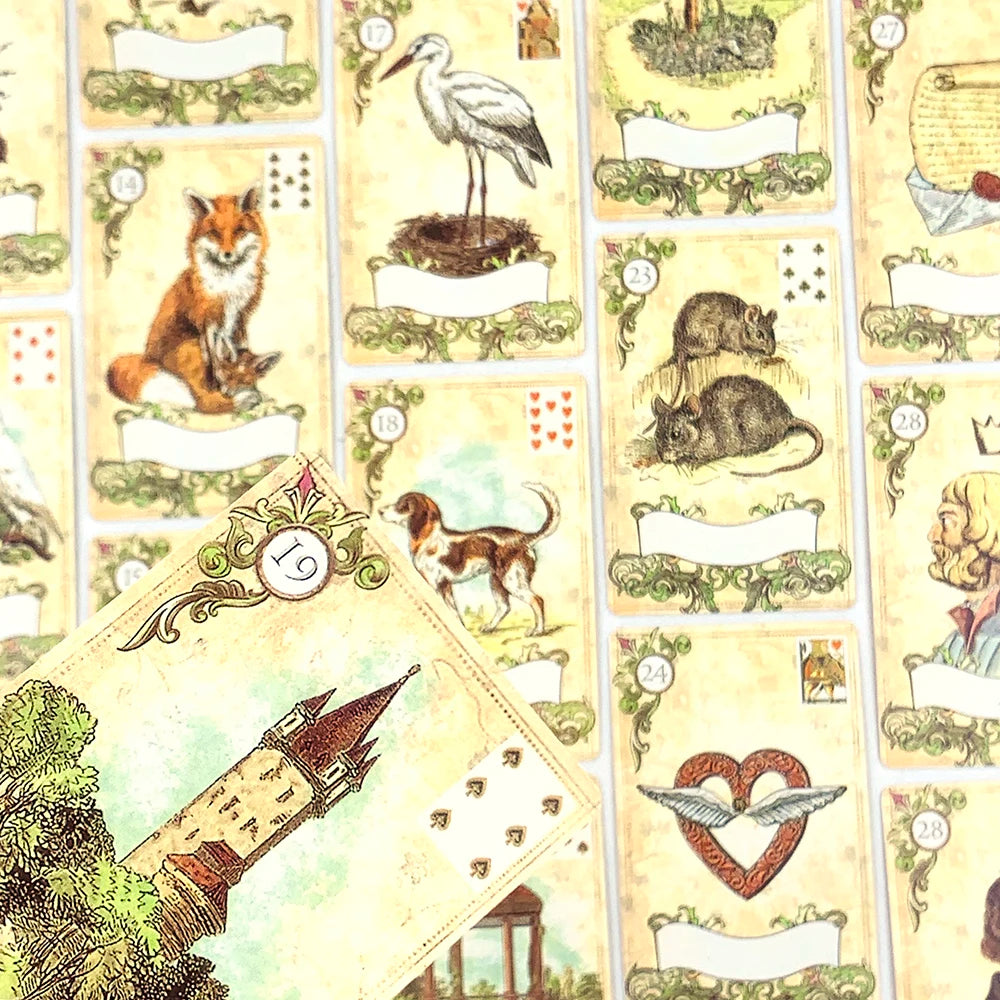 A close-up of a Lenormand oracle card deck featuring various animal and symbolic cards.