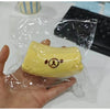 A yellow banana shaped squishy stress relief toy with a bear face design is held in a clear plastic bag.