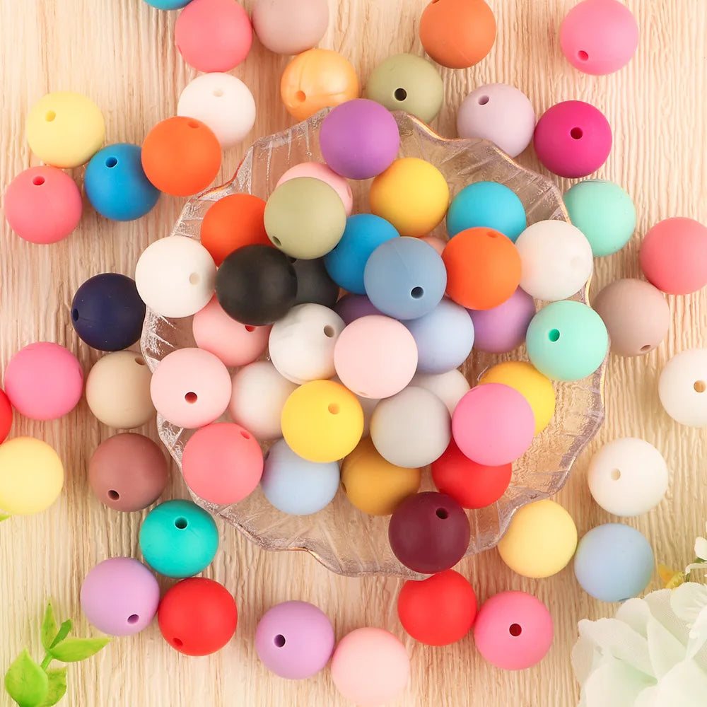 A collection of assorted colored silicone beads scattered on a light wooden surface for DIY jewelry making.