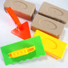 A set of three plastic molds in orange, tan, and yellow for making sand and snow bricks.